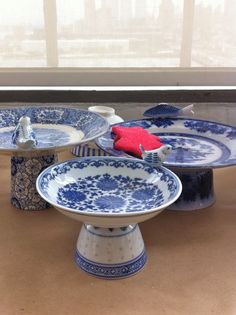 four blue and white plates sitting on top of a table next to a large window