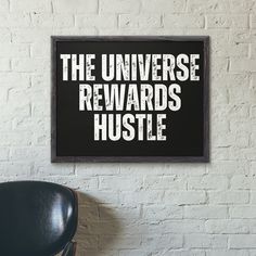 a black chair in front of a white brick wall with the words, the universe reward hustle on it