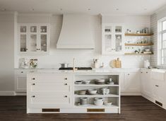 a kitchen with white cabinets and open shelves on the wall, along with wooden flooring