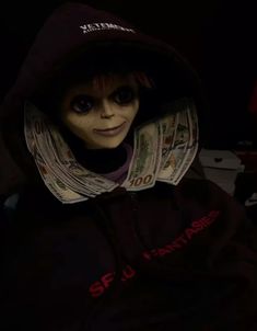 a creepy doll wearing a hoodie with money in it's mouth and eyes