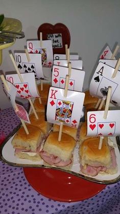 a table topped with lots of sandwiches and playing cards on top of each other,