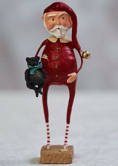 a figurine is holding a black cat and wearing a red outfit with gold bells