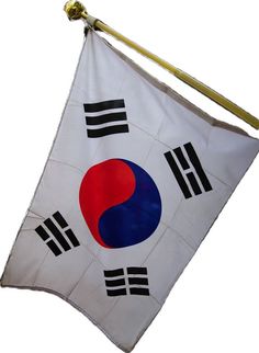 a white flag with black, red and blue designs hanging from a metal hook on a pole