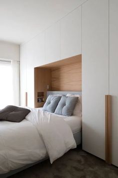 a white bed sitting next to a window in a bedroom on top of a carpeted floor