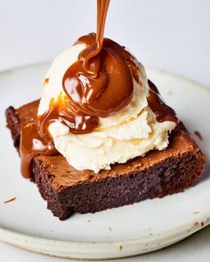 a piece of cake with ice cream and caramel sauce on top is sitting on a white plate