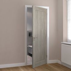 an empty room with a door open to reveal a bed in the corner and a radiator on the wall