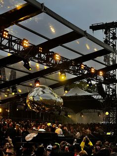 a large group of people standing on top of a stage with disco balls hanging from the ceiling