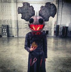 a person in a costume that looks like a cat with red eyes and horns holding a piece of food