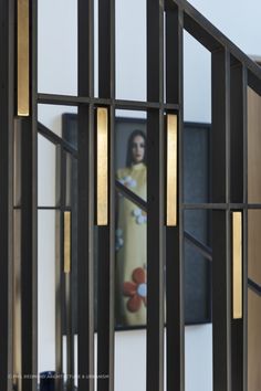 the reflection of a woman in a mirror is seen through an iron frame with gold accents