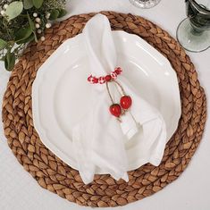 a place setting with two napkins and red beads on the handles, sitting on a wicker plate