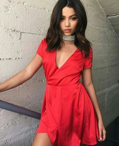 a woman in a red dress posing for the camera with her hands on her hips