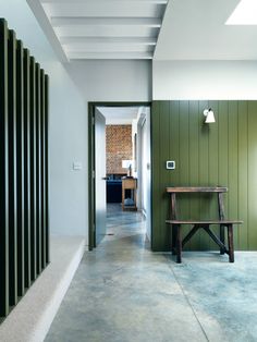 the hallway is painted green and has a wooden bench