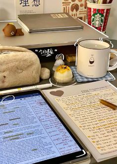 a table topped with an ipad computer next to a cup of coffee and other items