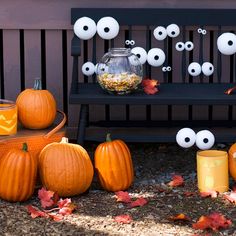 some pumpkins are sitting on the ground next to jars with eyes painted on them