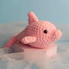 a pink crocheted stuffed animal laying on top of a piece of white tulle