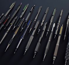 many different pens and pencils lined up on a black surface with one pen in the middle