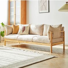 a white couch sitting on top of a hard wood floor next to a lamp and potted plant