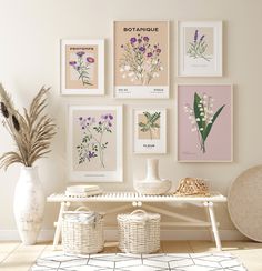 a white table topped with vases filled with flowers and plants next to pictures on the wall