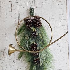 a wreath with pine cones and bells hanging on a wall