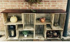 an old wooden cabinet with pumpkins and other decorations on it's sides, sitting in front of a brick wall