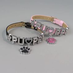 two dog collars with hearts and paw prints on them, one has a pink ribbon