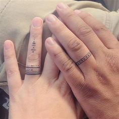 two people holding hands with tattoos on their fingers