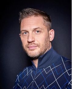 a close up of a person wearing a blue shirt and looking at the camera with a serious look on his face