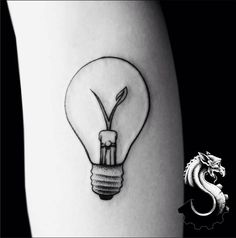 a tattoo with a light bulb on the thigh and a dragon in the back ground