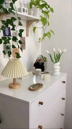 a white dresser topped with lots of green plants