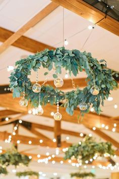 a chandelier hanging from the ceiling in a room filled with lights and greenery