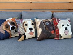 four pillows with dogs on them sitting on a couch