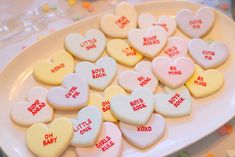 some heart shaped cookies are on a white platter with little ones written on them