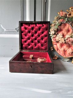 an open wooden box sitting on top of a table next to a vase with flowers