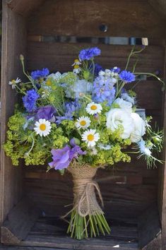 a bouquet of blue and white flowers in a wooden crate