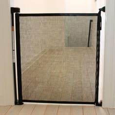 an open door with a screen on the inside of it in a room that has wood floors and white walls