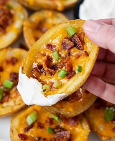 a hand is holding up an open cheese and bacon egg muffin on a white plate