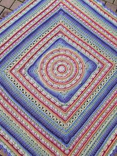 a crocheted blanket is laying on the ground