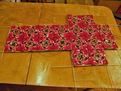 a cross made out of red and black tiles sitting on top of a wooden table