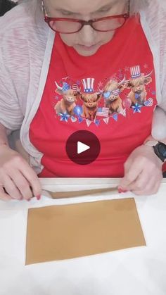 a woman is cutting paper with scissors on a white table and looking at the screen