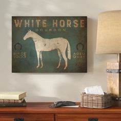 a white horse poster mounted on the wall above a wooden dresser with a lamp next to it