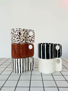 three coffee mugs sitting on top of a white tiled floor next to each other