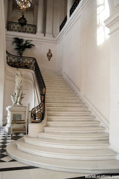 an ornate staircase leading up to the second floor with chandelier and marble busturine