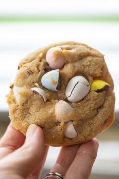 a person holding up a cookie with candy on it's side and the top half eaten