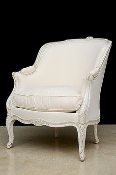 an old white chair sitting on top of a floor