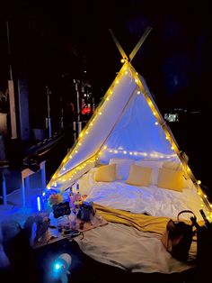 a tent that has lights on it in the middle of a room with pillows and blankets