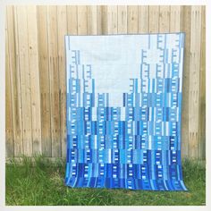 a blue and white quilt hanging from a wooden fence