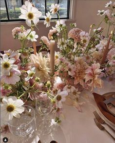 the table is set with flowers and candles for an elegant dinner or party setting in pastel tones