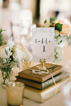 a table topped with books and vases filled with white flowers sitting on top of a table