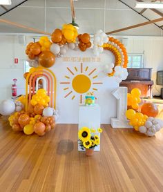 a room with balloons and sunflowers on the floor in front of an arch