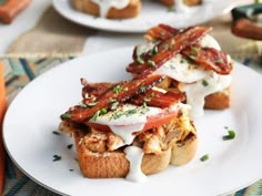 two sandwiches with bacon, cheese and sour cream on them sitting on a white plate